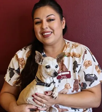 Ragina smiling while holding a dog